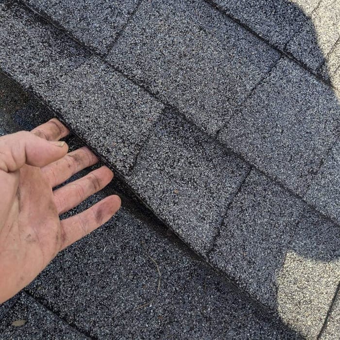 Close-up inspection of storm-damaged shingles