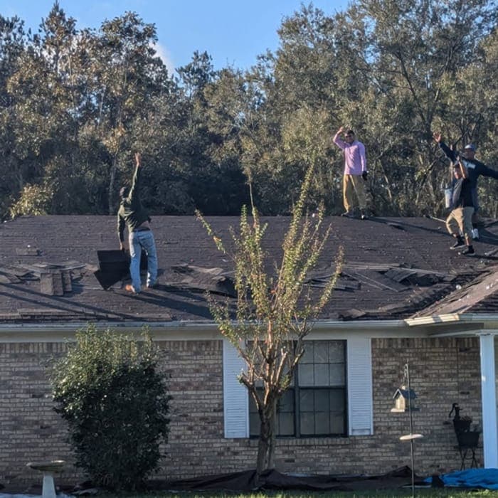 Lee Roofing crew waving from a roof tear-off